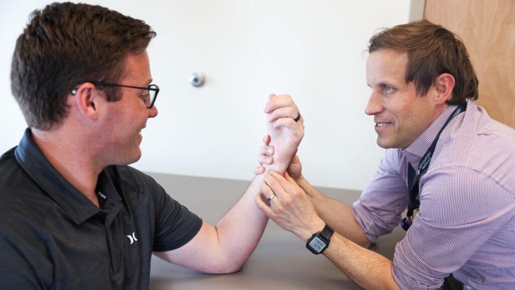 Dr. Patrick R. Olson examining a male patient's wrist.